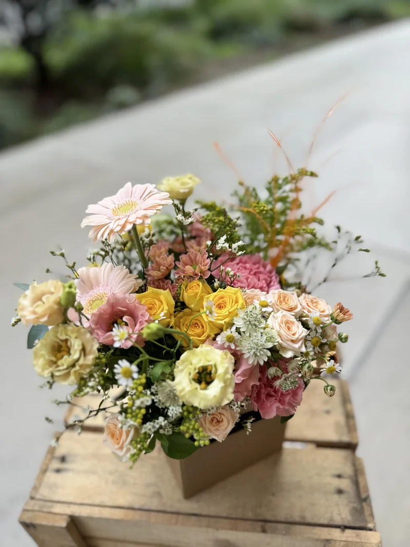 Arrangement floral Le Cubique, composé de fleurs frâiches dans les tons rose et jaune selon fleurs de saison